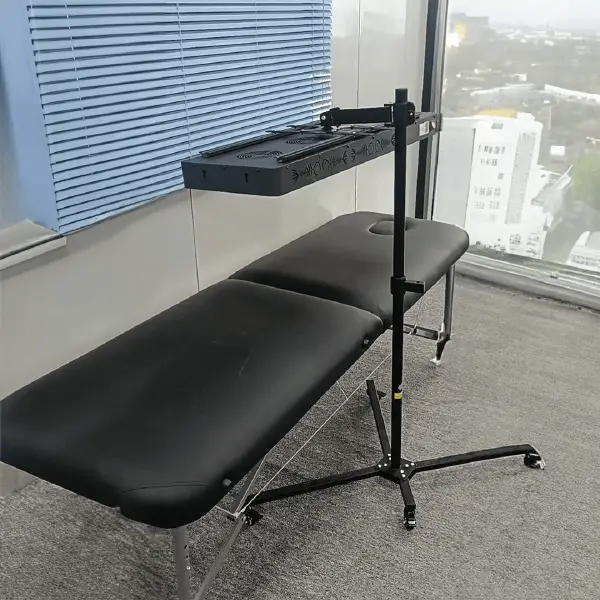 Red light panel mounted on adjustable 360 stand above massage table